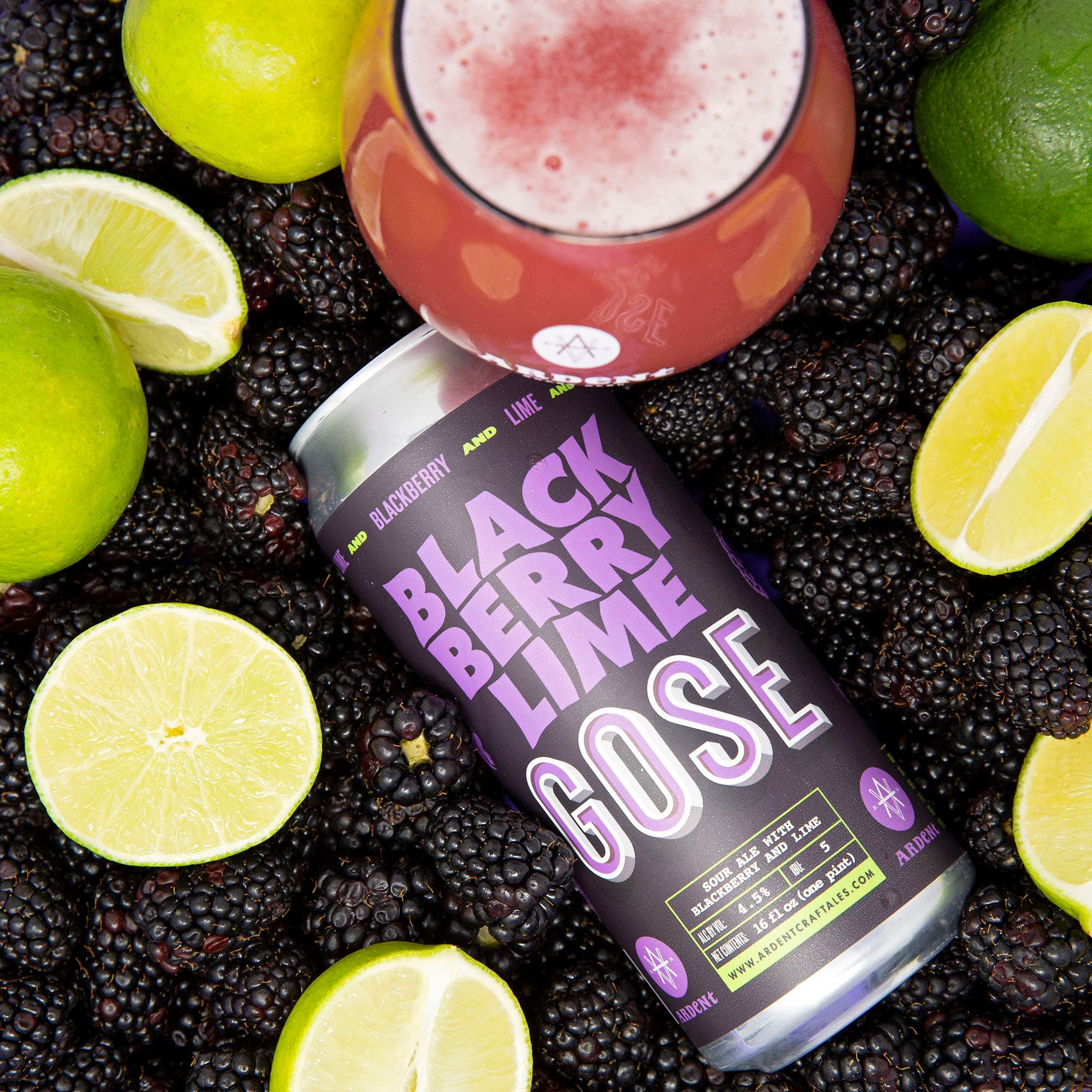 Overhead view of black can of Blackberry Lime Gose laying in a bed of whole blackberries surrounded by fresh cut limes