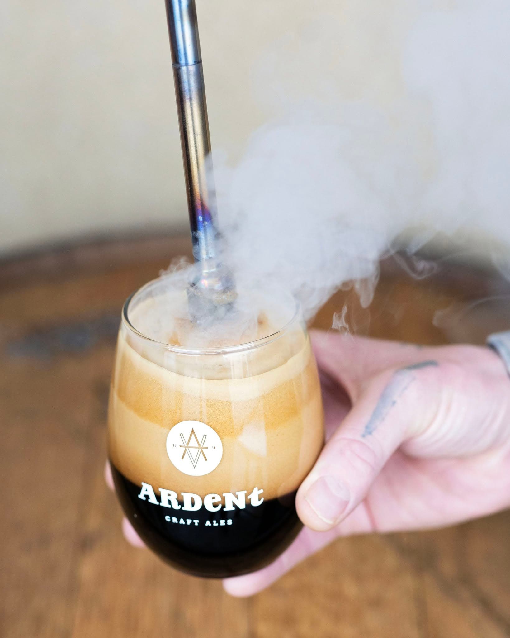 Smoke rising out of a glass of beer as it is poked by a hot rod