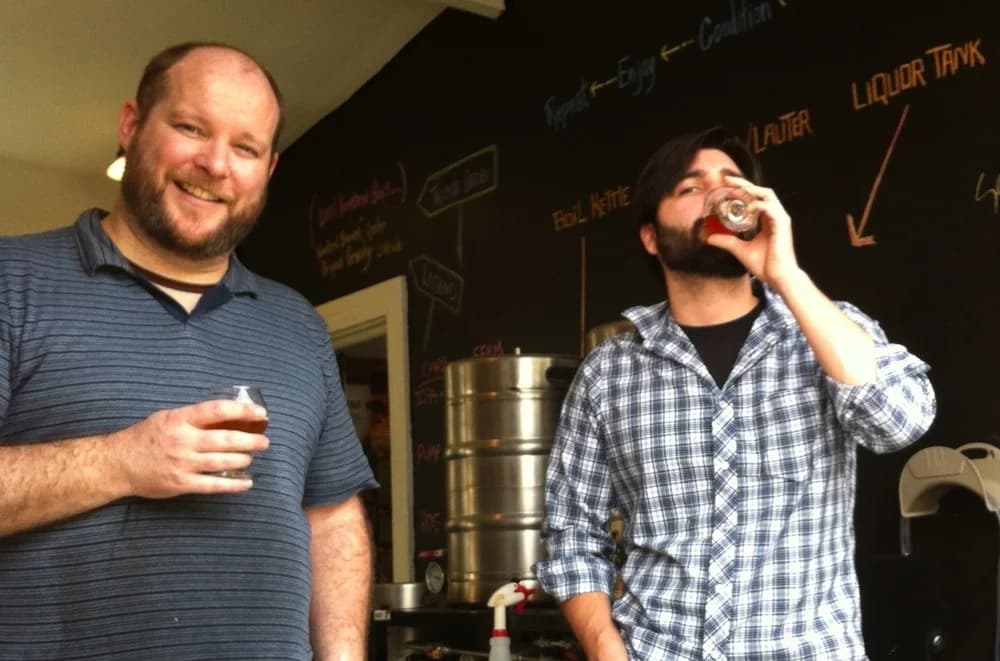 Vintage photo of two men drinking beer samples inside a garage