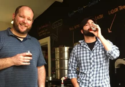 Vintage photo of two men drinking beer samples inside a garage