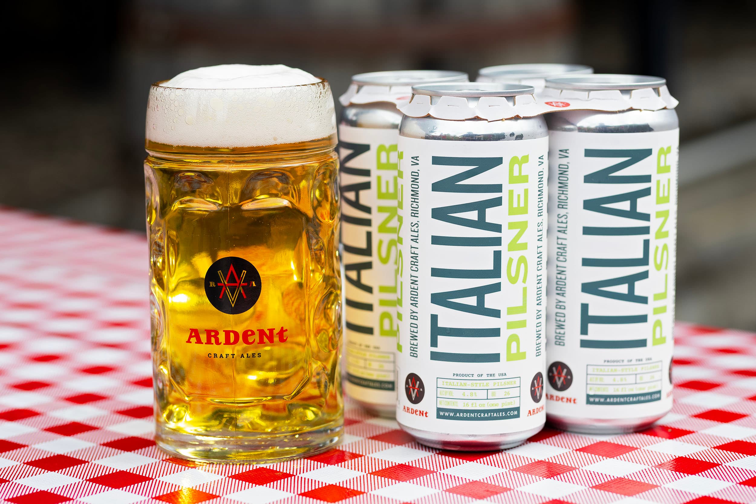 4-pack of dark blue 16oz cans of Bohemian Pilsner next to stein full of clear golden lager